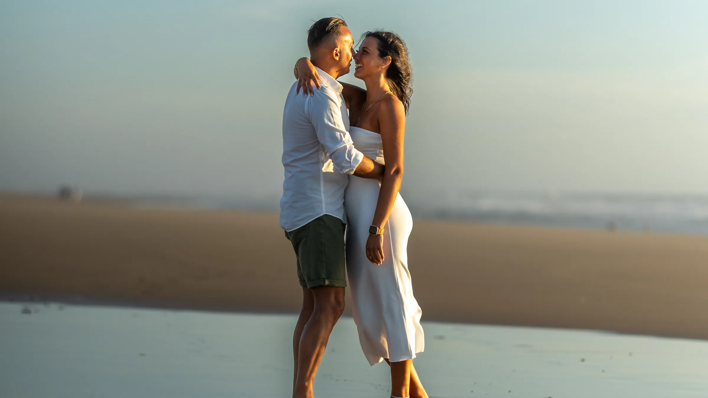 Casal abraçado na praia ao entardecer