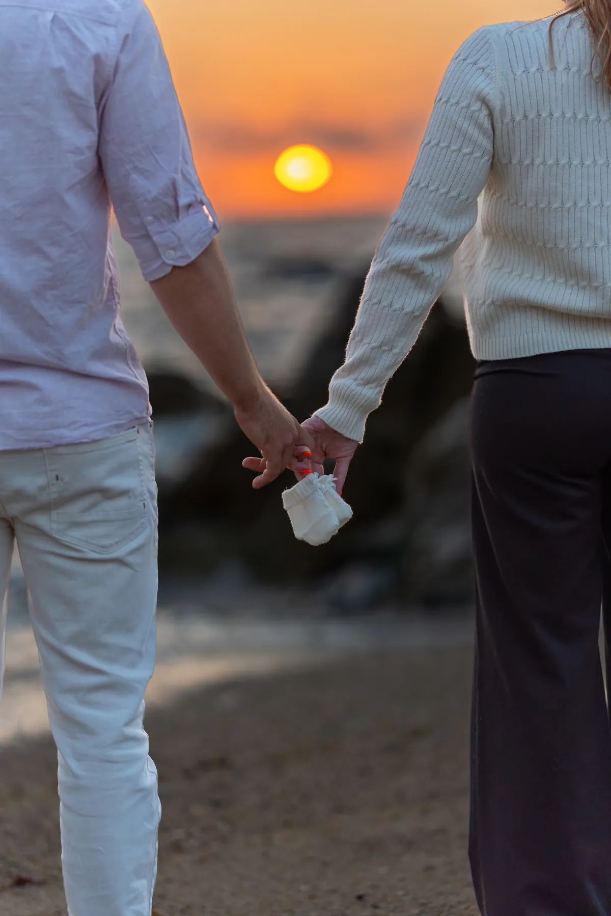 Casal de mãos dadas em frente ao pôr do sol