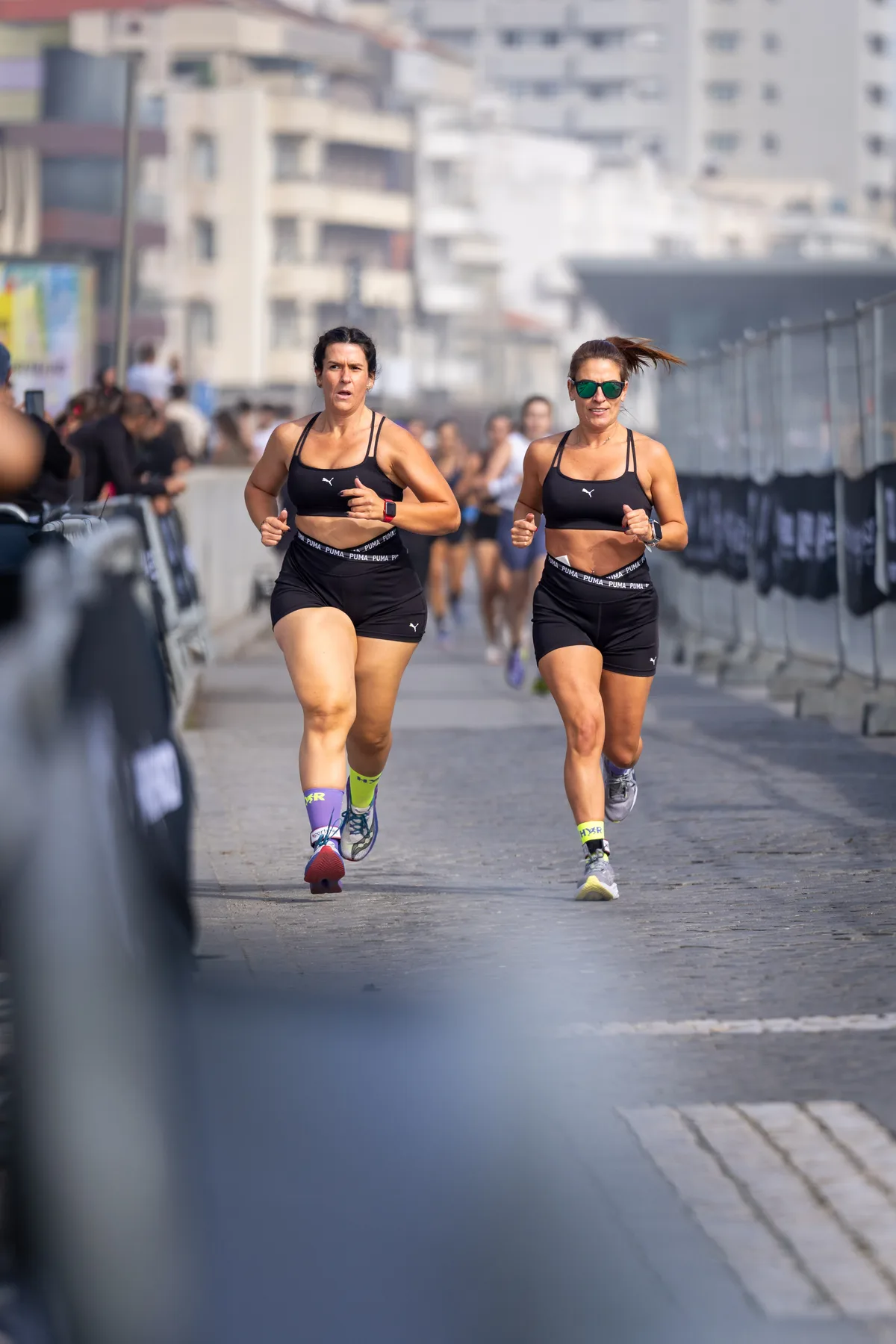 Duas atletas a correr lado a lado numa prova de rua