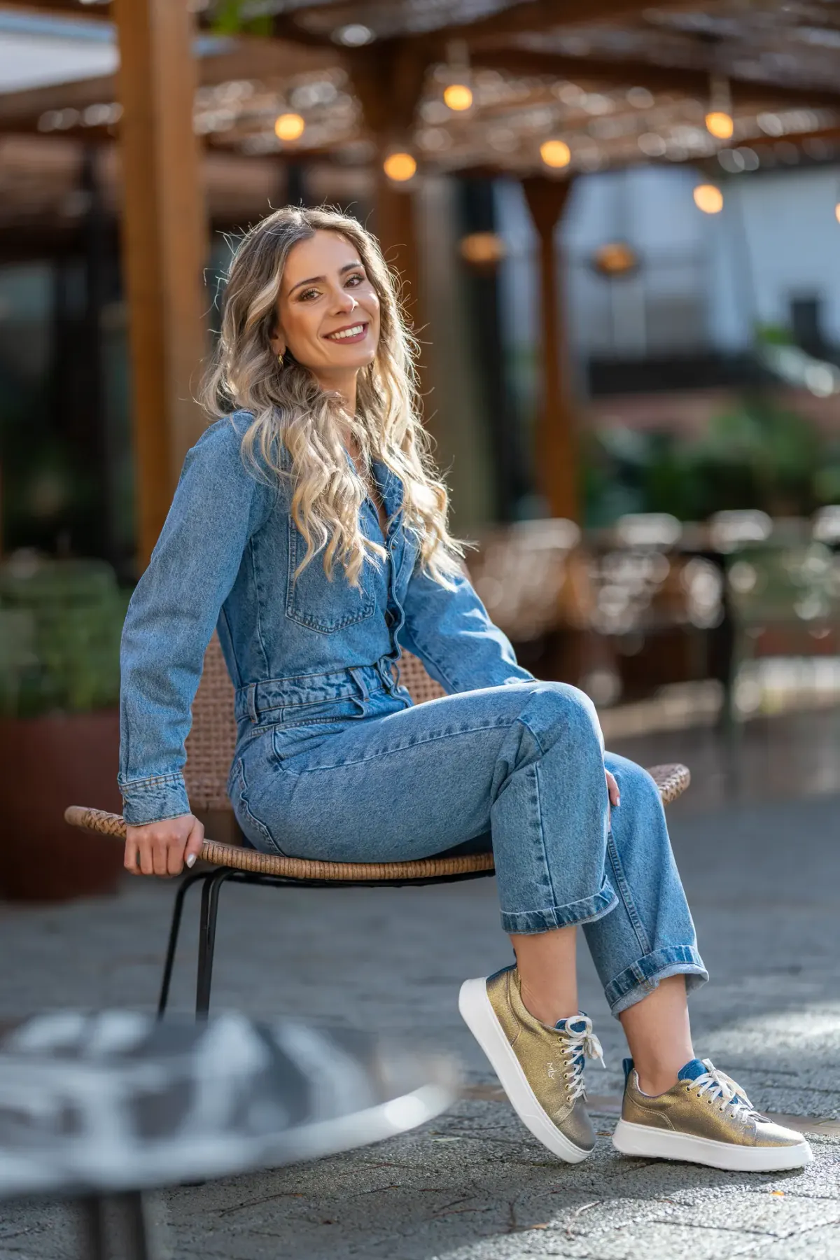 Mulher de camisa pastel, sentada e de olhar sereno, numa sessão de conteúdo para redes sociais