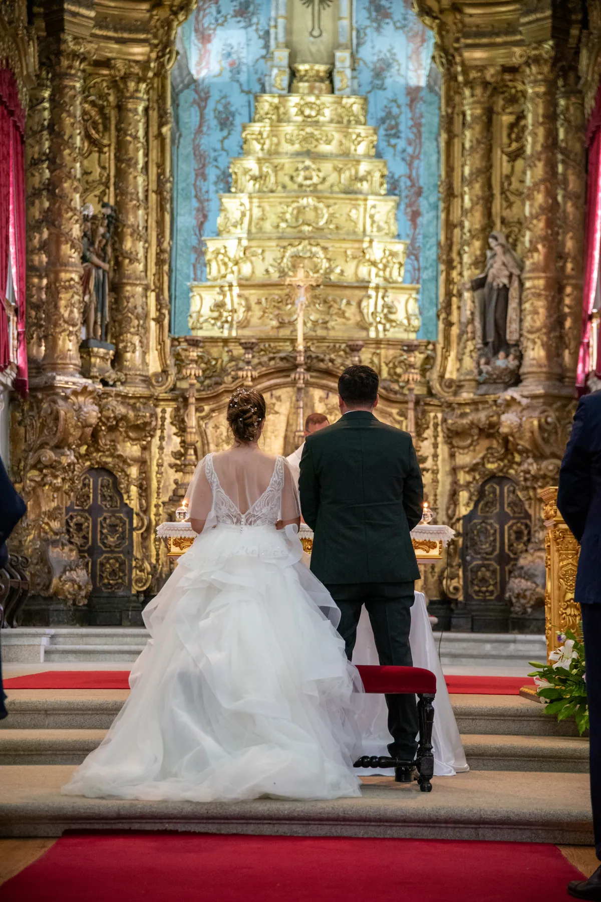 Noivos de costas diante de um altar dourado, na igreja